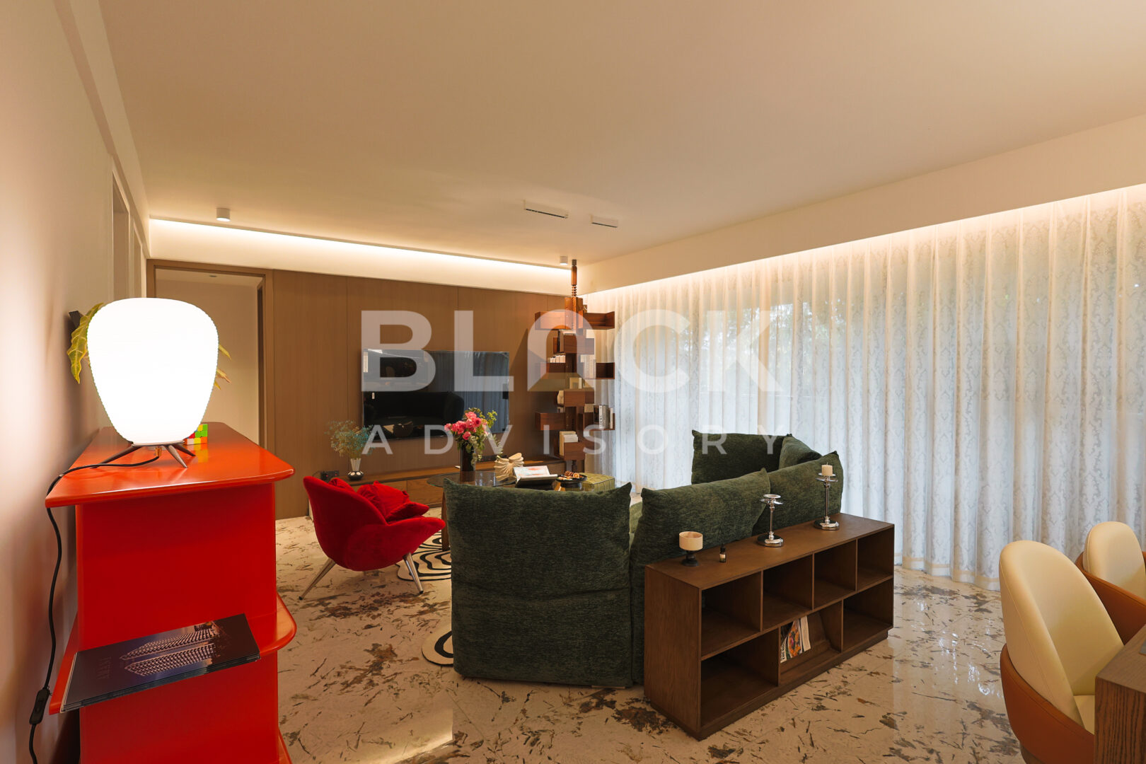 Amani Residence show apartment living room with a green sofa, a red side table and a sideboard