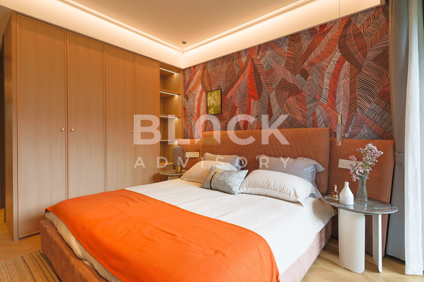 Amani Residence show apartment main bedroom with an orange throw and a patterned feature wall