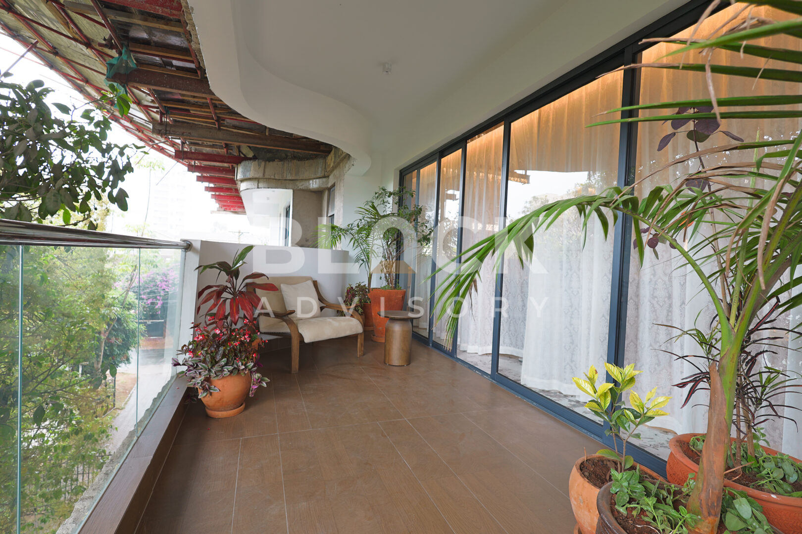 Amani Residence show apartment balcony with potted plants, a glass balustrade and outdoor seating