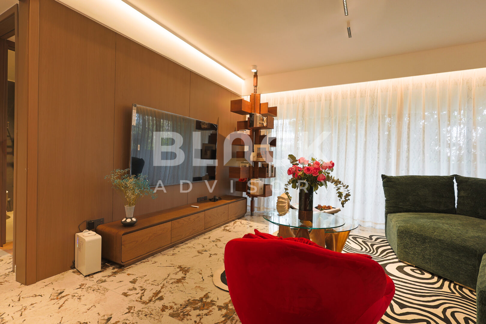 Amani Residence show apartment living room with a timber TV wall, a red armchair and a green sofa
